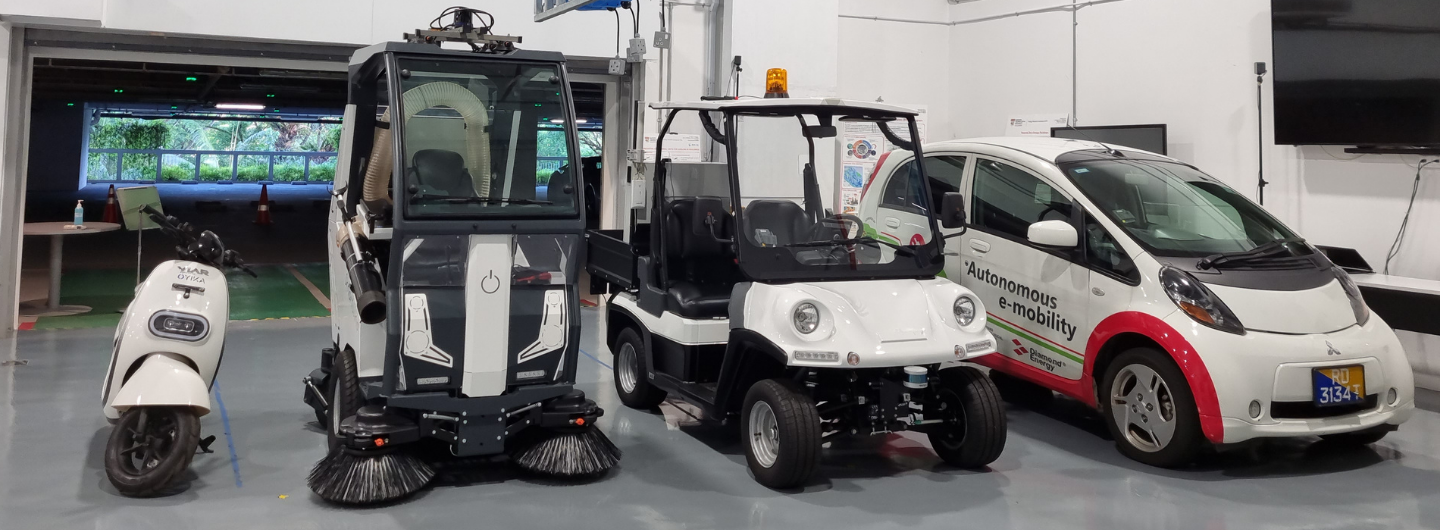 Indoor shot of a YLAR Oyika e-scooter, street sweeper, golf cart, and Mitsubishi i-MiEV with Autonomous e-mobility label